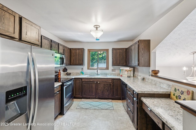 5041 E Willoughby Rd Unit 7, Holt, MI 48842 - kitchen with appliances with stainless steel finishes, dark brown cabinets, and hanging light fixtures