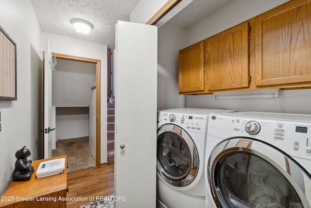 5041 E Willoughby Rd Unit 7, Holt, MI 48842 - washroom with cabinet space, separate washer and dryer, light wood-style flooring, and a textured ceiling