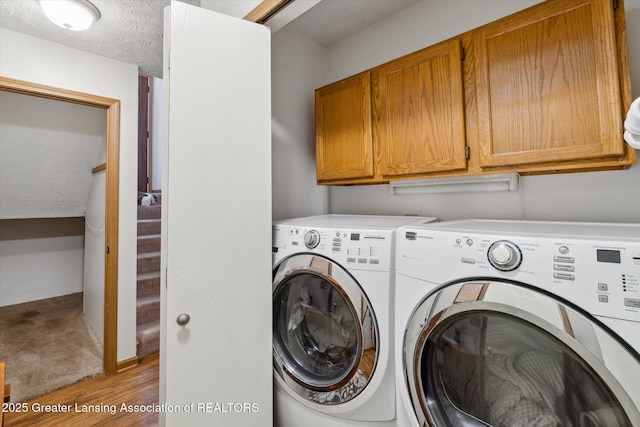 5041 E Willoughby Rd Unit 7, Holt, MI 48842 - laundry room featuring separate washer and dryer, light wood-style floors, cabinet space, and a textured ceiling