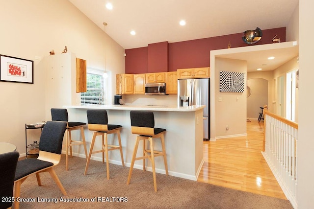 4001 Sierra Hts, Holt, MI 48842 - kitchen with appliances with stainless steel finishes, light brown cabinetry, a breakfast bar, high vaulted ceiling, and arched walkways