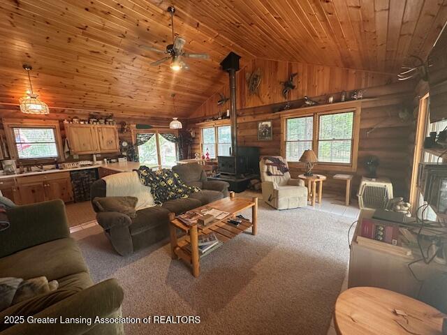 10886 SE Gillow Rd, Fife Lake, MI 49633 - living room featuring lofted ceiling, a wood stove, wood ceiling, healthy amount of natural light, and a ceiling fan