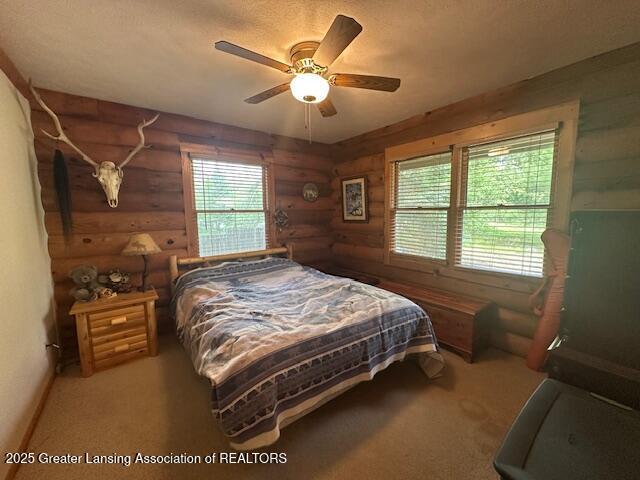 10886 SE Gillow Rd, Fife Lake, MI 49633 - bedroom with rustic walls, ceiling fan, and carpet