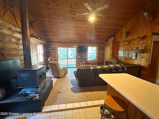 10886 SE Gillow Rd, Fife Lake, MI 49633 - living room with lofted ceiling, wooden ceiling, rustic walls, a wood stove, and a ceiling fan