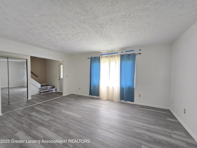 3116 Colchester Rd, Lansing, MI 48906 - unfurnished living room featuring stairs, wood finished floors, and a textured ceiling