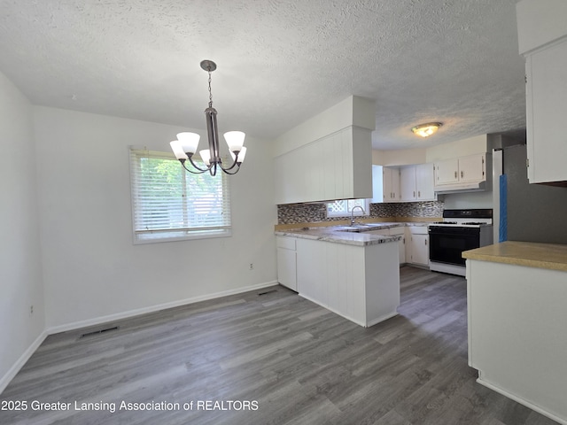 3116 Colchester Rd, Lansing, MI 48906 - kitchen featuring white gas range oven, freestanding refrigerator, a textured ceiling, white cabinetry, and a chandelier