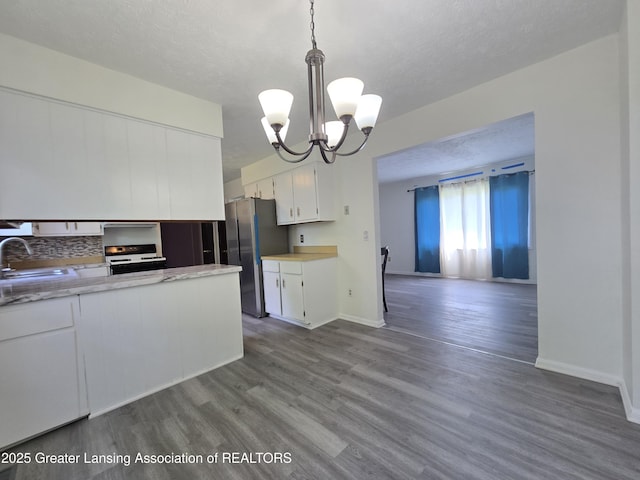3116 Colchester Rd, Lansing, MI 48906 - kitchen featuring freestanding refrigerator, white cabinets, light countertops, white gas range, and a chandelier