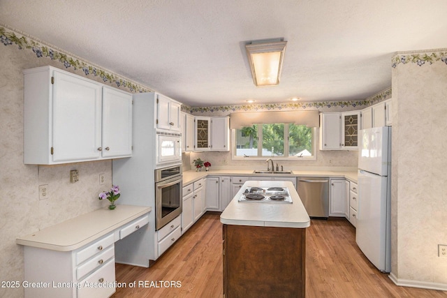 5800 Bent Tree Dr, East Lansing, MI 48823 - kitchen featuring stainless steel appliances, light wood finished floors, light countertops, glass insert cabinets, and wallpapered walls