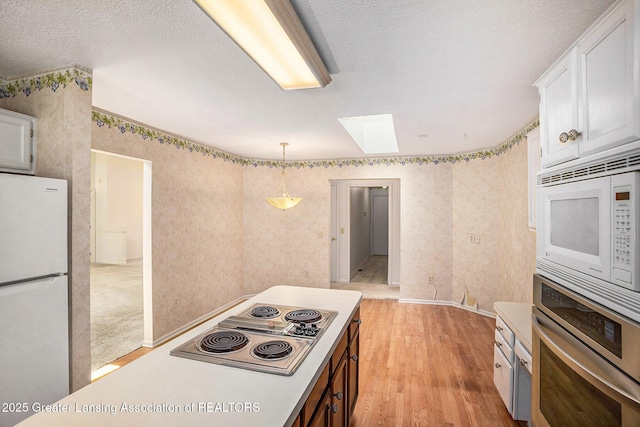 5800 Bent Tree Dr, East Lansing, MI 48823 - kitchen with stainless steel appliances, a skylight, light wood-type flooring, white cabinets, and hanging light fixtures