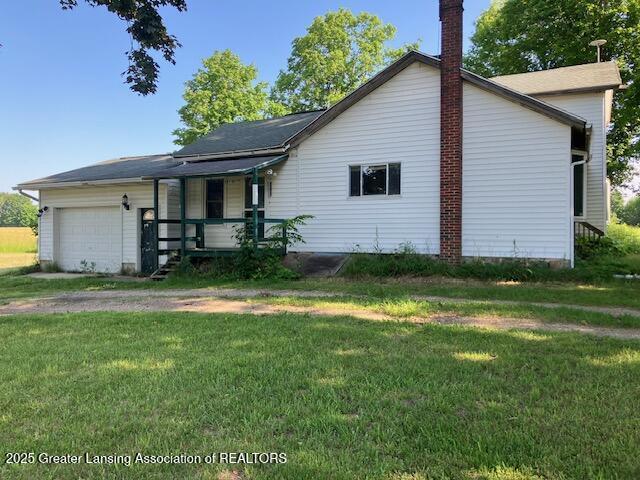4405 Otto Rd, Charlotte, MI 48813 - view of front of house featuring a porch, a garage, a front lawn, a chimney, and dirt driveway