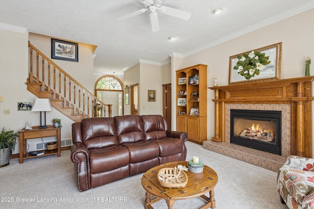 169 Mapleview Dr, Charlotte, MI 48813 - living area with light carpet, crown molding, a ceiling fan, a tiled fireplace, and stairs
