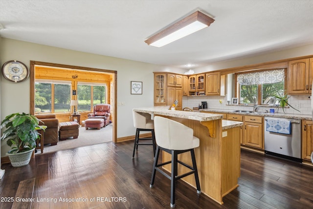 169 Mapleview Dr, Charlotte, MI 48813 - kitchen with dishwasher, a breakfast bar area, decorative backsplash, glass insert cabinets, and light stone countertops