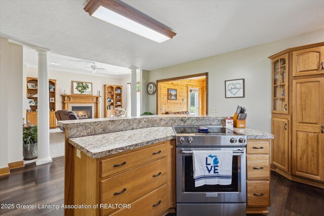 169 Mapleview Dr, Charlotte, MI 48813 - kitchen with stainless steel range with electric stovetop, ornate columns, a warm lit fireplace, and dark wood-type flooring
