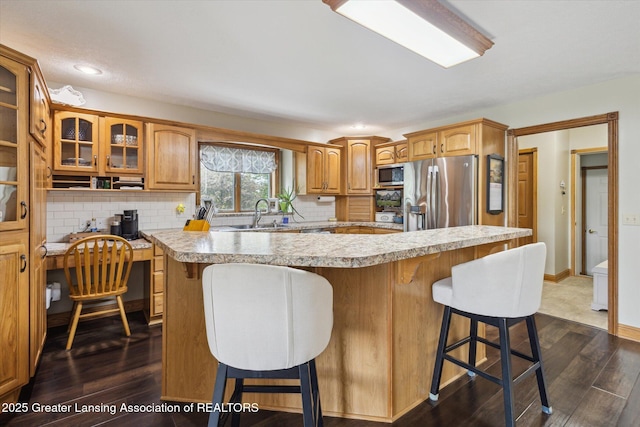 169 Mapleview Dr, Charlotte, MI 48813 - kitchen featuring appliances with stainless steel finishes, light countertops, a kitchen bar, glass insert cabinets, and decorative backsplash