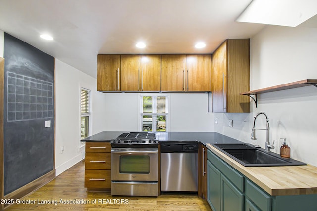 416 E Elm St, Mason, MI 48854 - kitchen with appliances with stainless steel finishes, a peninsula, light wood-style floors, recessed lighting, and wooden counters