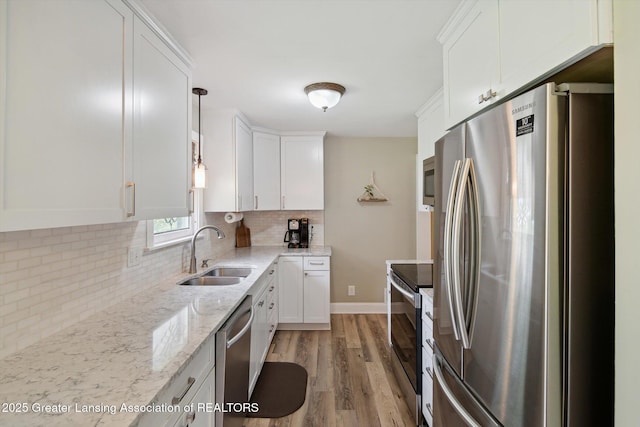 6244 Daft St, Lansing, MI 48911 - kitchen featuring appliances with stainless steel finishes, white cabinetry, light wood-style flooring, and tasteful backsplash