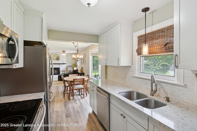 6244 Daft St, Lansing, MI 48911 - kitchen featuring appliances with stainless steel finishes, light wood-style floors, tasteful backsplash, and white cabinets