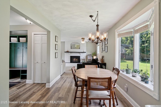 6244 Daft St, Lansing, MI 48911 - dining space featuring a fireplace, light wood finished floors, and a chandelier