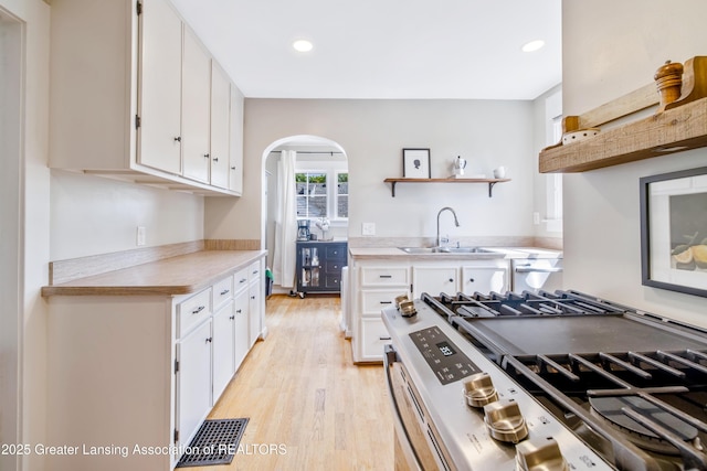 308 Memphis St, Lansing, MI 48915 - kitchen with stainless steel range with gas cooktop, arched walkways, white cabinets, light wood-type flooring, and open shelves
