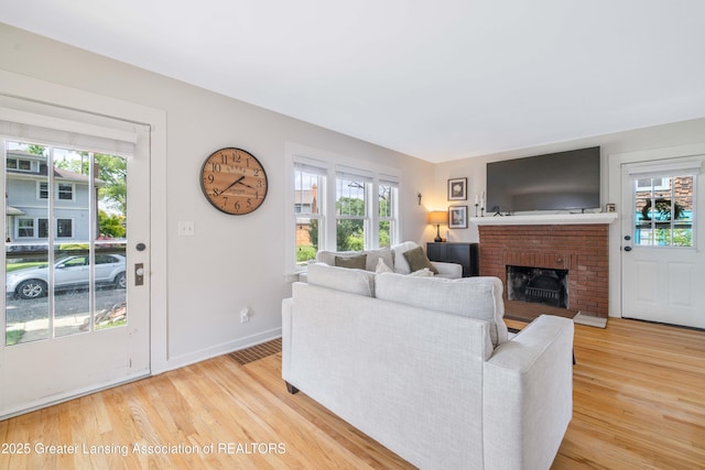 308 Memphis St, Lansing, MI 48915 - living room featuring plenty of natural light, light wood finished floors, and a brick fireplace