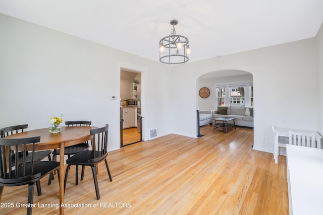 308 Memphis St, Lansing, MI 48915 - dining space featuring arched walkways, light wood finished floors, and a chandelier