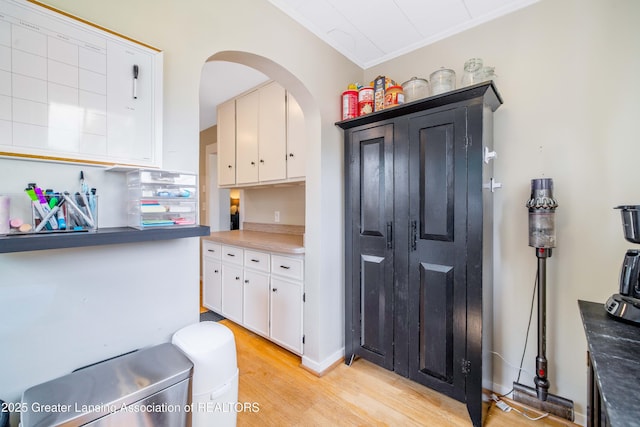 308 Memphis St, Lansing, MI 48915 - kitchen with light wood-style floors, white cabinets, arched walkways, and crown molding