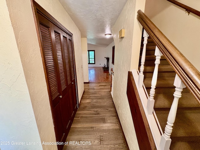 12830 Upton Rd, Bath, MI 48808 - hallway with hardwood / wood-style flooring, a textured wall, a textured ceiling, and stairway
