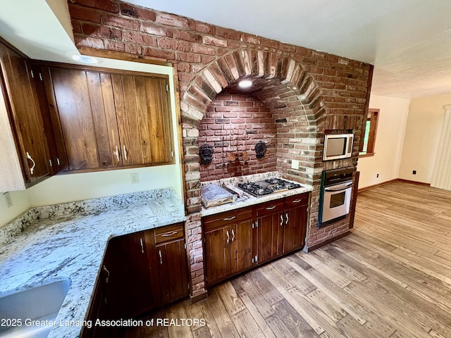 12830 Upton Rd, Bath, MI 48808 - kitchen with stainless steel appliances, brick wall, light wood finished floors, and dark brown cabinetry