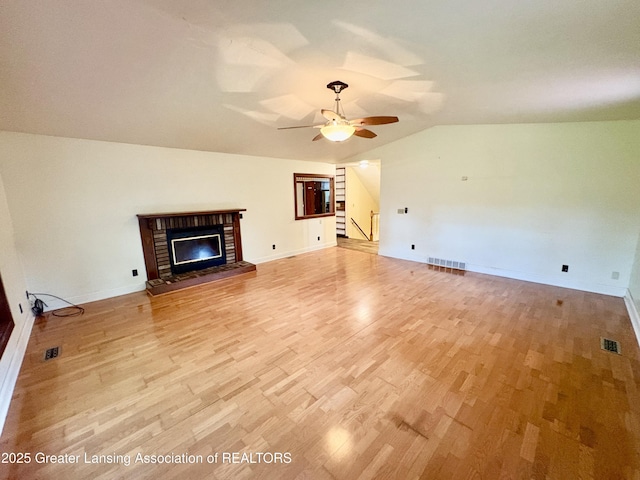 12830 Upton Rd, Bath, MI 48808 - unfurnished living room featuring lofted ceiling, light wood-style flooring, a fireplace, ceiling fan, and stairs