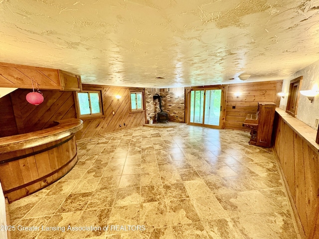 12830 Upton Rd, Bath, MI 48808 - unfurnished living room with wooden walls and a wood stove
