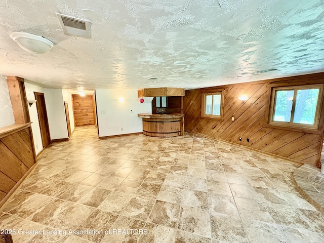 12830 Upton Rd, Bath, MI 48808 - unfurnished living room with wood walls and light stone finish floors