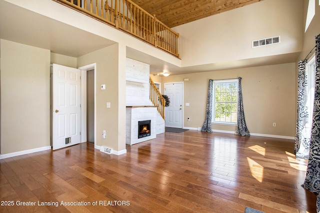 7563 6 Mile Rd, East Leroy, MI 49051 - unfurnished living room with a high ceiling, wood finished floors, a tiled fireplace, and wooden ceiling