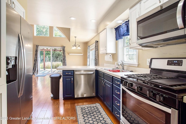 7563 6 Mile Rd, East Leroy, MI 49051 - kitchen with appliances with stainless steel finishes, blue cabinetry, a peninsula, white cabinetry, and dark wood-type flooring
