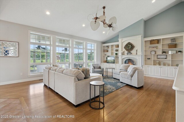 5056 W Bunker Rd, Mason, MI 48854 - living room with recessed lighting, plenty of natural light, wood finished floors, high vaulted ceiling, and a lit fireplace