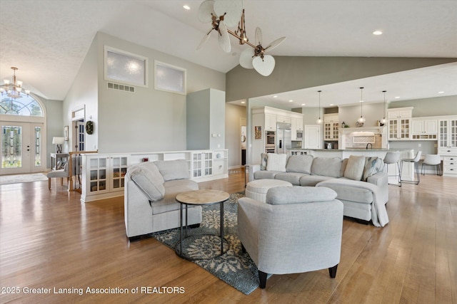 5056 W Bunker Rd, Mason, MI 48854 - living area featuring a chandelier, high vaulted ceiling, and light wood-type flooring