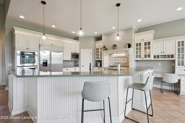 5056 W Bunker Rd, Mason, MI 48854 - kitchen featuring built in appliances, recessed lighting, glass insert cabinets, a kitchen bar, and a large island with sink