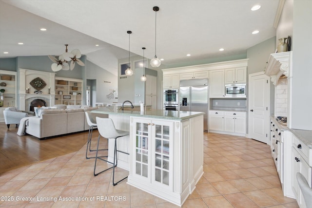 5056 W Bunker Rd, Mason, MI 48854 - kitchen with built in appliances, a warm lit fireplace, lofted ceiling, light tile patterned flooring, and a breakfast bar