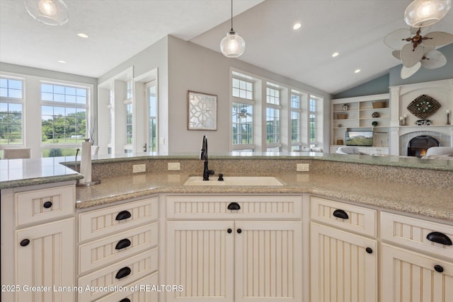 5056 W Bunker Rd, Mason, MI 48854 - kitchen with ceiling fan, open floor plan, recessed lighting, a warm lit fireplace, and light stone countertops