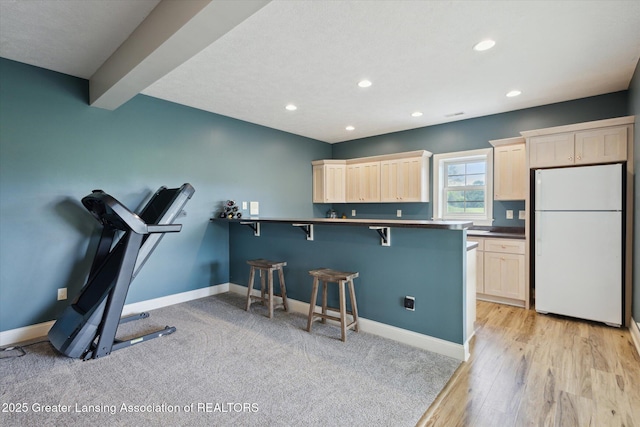 5056 W Bunker Rd, Mason, MI 48854 - kitchen with freestanding refrigerator, a breakfast bar, dark countertops, recessed lighting, and light brown cabinets