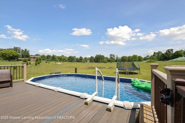 5056 W Bunker Rd, Mason, MI 48854 - outdoor pool with a trampoline, a wooden deck, a lawn, and view of scattered trees