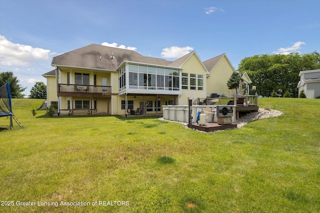5056 W Bunker Rd, Mason, MI 48854 - rear view of house with a sunroom, a hot tub, a wooden deck, and a trampoline