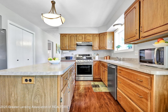 5925 Cabrena Dr, Lansing, MI 48917 - kitchen with appliances with stainless steel finishes, under cabinet range hood, dark wood-style flooring, light countertops, and a center island