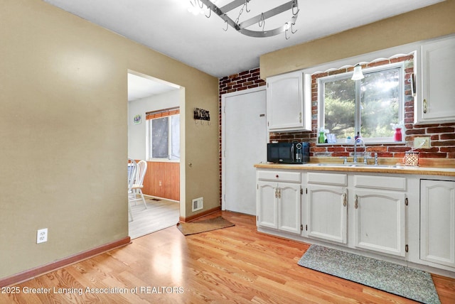 314 Scarlet Oak Ln, Perry, MI 48872 - kitchen with white cabinets, light wood-style flooring, light countertops, tasteful backsplash, and black microwave