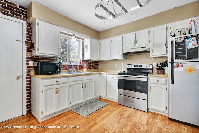 314 Scarlet Oak Ln, Perry, MI 48872 - kitchen featuring stainless steel electric range oven, freestanding refrigerator, black microwave, under cabinet range hood, and white cabinetry