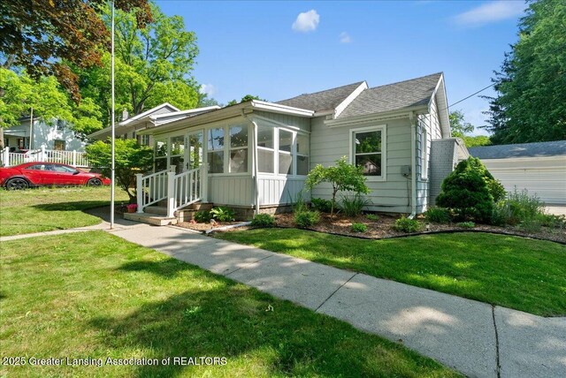 520 Wood St, Eaton Rapids, MI 48827 - view of front of property with roof with shingles, a front yard, and a sunroom