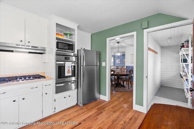 520 Wood St, Eaton Rapids, MI 48827 - kitchen with stainless steel appliances, a warming drawer, under cabinet range hood, light wood finished floors, and tasteful backsplash