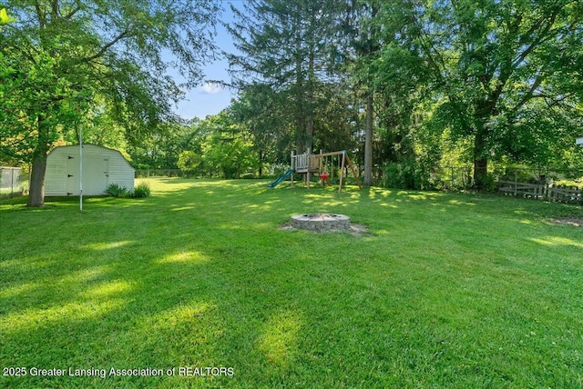 520 Wood St, Eaton Rapids, MI 48827 - fenced backyard featuring a playground, a fire pit, and a storage unit