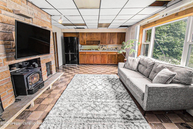 13433 S Grange Rd, Eagle, MI 48822 - living room featuring a wood stove, a drop ceiling, and light floors
