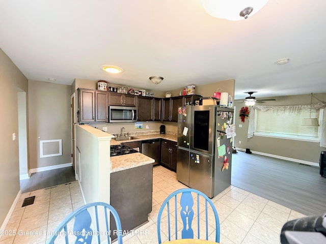 874 Brookdale St, Mason, MI 48854 - kitchen with appliances with stainless steel finishes, dark brown cabinets, ceiling fan, and light stone countertops