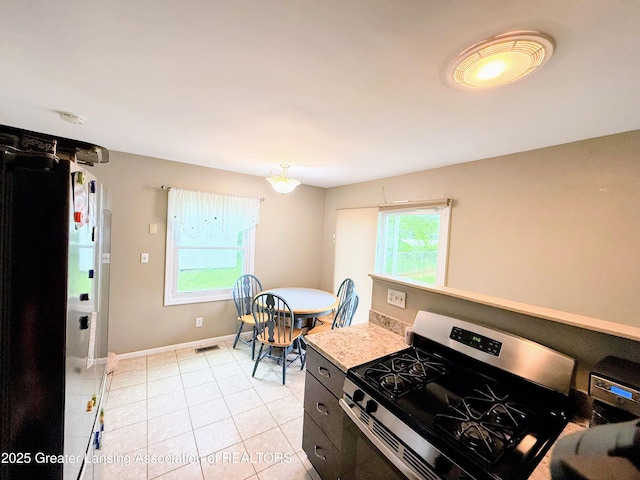874 Brookdale St, Mason, MI 48854 - kitchen with stainless steel gas range, light tile patterned floors, and light countertops