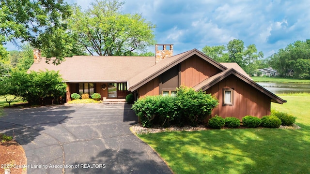 280 Winterberry Ln, Okemos, MI 48864 - view of front facade with board and batten siding, a chimney, a front yard, and asphalt driveway